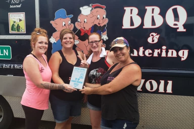Four Three Little Piggies BBQ staff members holding award in front of food truck
